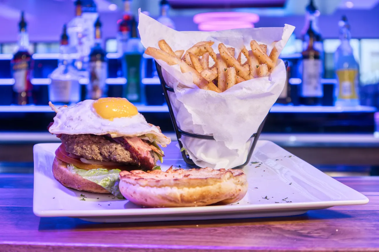 Burger topped with a fried egg with seasoned fries